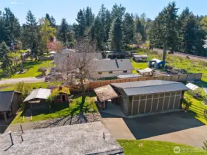 This ariel view shows the edge of the house rooftop, large dog run area, 2 car detached shop w/ small carport for storing wood & the edge of the garden area.