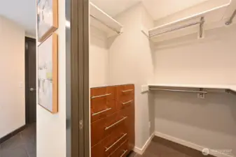 Primary walk-in closet with custom walnut built in drawers.