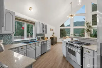 Open-concept layout with vaulted ceilings and abundant light flooding through the dramatic floor-to-ceiling windows overlooking the lake. This updated kitchen is equipped with modern stainless appliances including gas stove/range situated where you can cook with a view.