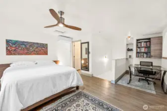 Primary bedroom with mini-split located next to bathroom entrance on left, stairway in the middle and nook on the right with extra built-ins for storage use, and a peak-a-boo view of the lake.