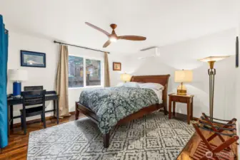 Downstairs bedroom is spacious featuring a ceiling fan and closet, space for small desk and other furniture such as dressers. Located at end of hallway off entryway, next to downstairs bathroom and with a closet that shares a wall with the living room.
