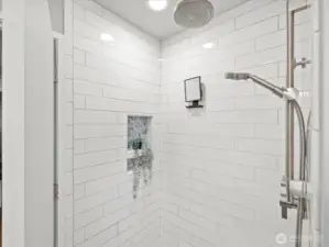 Main level walk in shower with rain shower head and separate handheld shower fixture.