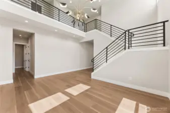 Grand open-concept foyer with modern railing, chandelier lighting, and balcony overlook—ideal for showcasing contemporary Northwest architecture.