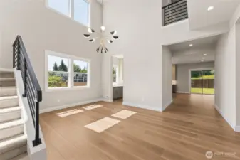 Soaring two-story foyer with modern light fixture, oversized windows, and natural hardwood flooring—designed to impress from the moment you step inside.