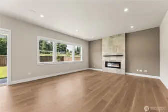 Modern open-concept living room featuring wide-plank hardwood floors, large energy-efficient windows, and a contemporary tile fireplace—perfect for natural light and indoor-outdoor living.