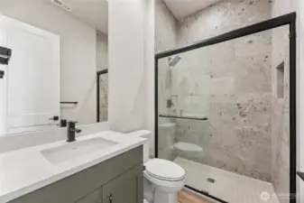 Modern guest bathroom featuring a quartz countertop, sleek matte black fixtures, and a full tile walk-in shower with glass enclosure.