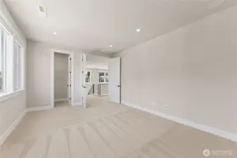 Bright upstairs bedroom with walk-in closet, plush carpet, and an open feel overlooking the loft.