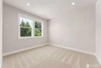 Secondary bedroom with fresh carpet, large picture windows, and peaceful views of lush evergreens—perfect for a guest room or home office.