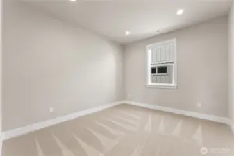 Spacious secondary bedroom with neutral tones, plush carpet, and recessed lighting.