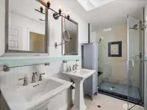 Primary bathroom with walk in shower stall & two sinks.