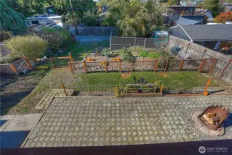 Looking down in to your yard.  HUGE patio- this home is an entertainer's dream.  Fun firepit is just one of the quirky pieces you will find in your yard.  Most yard art stays. The double gate was made out of jail cell doors- so much personality.   Patio, grass area, raised beds, then the chicken condo (gated area with the chicken trailer and 4 chickens.)  Fresh eggs, fresh herbs, fresh veggies, and fresh fruit.  Urban homesteading at its best.