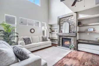 Framing the stone fireplace, custom floating wood shelves offer the perfect place to display photos, décor, and cherished keepsakes, adding warmth and character to this inviting living space.