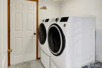 Laundry room located off of kitchen with door leading to garage.   Newer washer and dryer (2021) stays with the home.