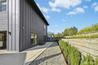 The backyard of the home with a landscaped terrace area that also has space and sun for a vegetable or flower garden.