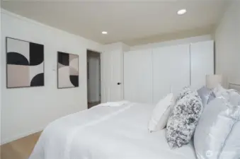 Minimalist bedroom with sleek, glossy custom closet for stylish storage.