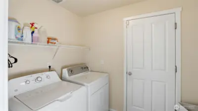 Convenient lower level laundry room with built-in shelving for easy organization and storage.