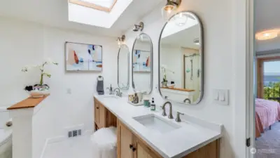 Updated primary bathroom boasts dual sinks, skylights, heated floors and walk-in shower.