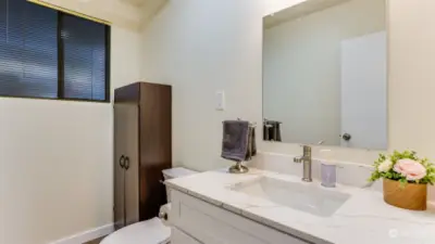 The utility room is downstairs with a half bath featuring fresh white walls, modern vanity, and ample storage space.