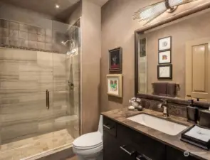 The guest bath is equally stunning with its marble topped vanity and natural stone surround tiles.