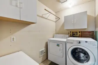 Efficient laundry area with upper cabinets and folding space—tucked in the garage for convenience and noise separation from the main living areas