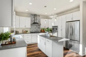 White shaker cabinetry, a spacious island with pendant lighting, and grey solid surface countertops