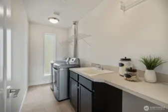A well-appointed laundry room with side-by-side washer and dryer, utility sink, and natural light provide comfort and functionality for everyday living
