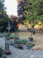 One more view from the base of the deck looking at the back yard, garden area, the the field with play structure beyond the fence.