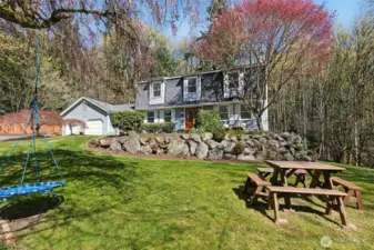 Well-maintained landscaping complemented by a park bench and multiple swings throughout the property.
