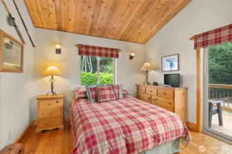 Primary bedroom with balcony overlooking the rear garden and forest