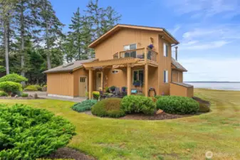 Rear view of the house, primary suite balcony, patio, garage access, small wood storage shelter