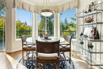 Sunny breakfast nook surrounded by windows, with access to an expansive deck and backyard.