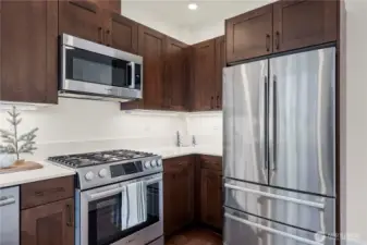 A closer look at the high-end appliance package, including a gas range, convection microwave, and French-door refrigerator. The warm wood cabinetry provides excellent storage and ties in beautifully with the home’s modern finishes.