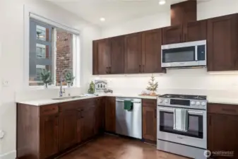 This corner of the kitchen highlights the oversized window above the sink, providing refreshing natural light and an airy feel. The deep sink and high-arc pull-down faucet add style and functionality to the workspace.