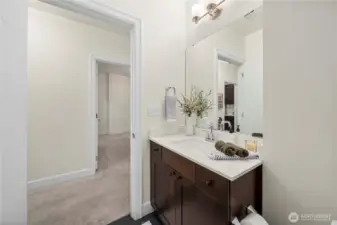 This view highlights the convenient hallway location of the main full bath, ideal for guests or everyday use. The broad vanity, updated fixtures, and generous mirror enhance both function and style, complementing the home’s cohesive finishes.