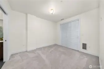 This bright primary bedroom features a spacious layout with plush carpeting and neutral finishes, creating a comfortable retreat. A large sliding door brings in natural light and offers convenient access to the outdoor space.