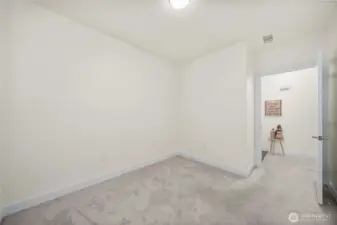 Another view of Secondary Bedroom showcases its open floor area and convenient hallway access. This flexible space adapts to your lifestyle needs and offers a peaceful retreat within the home’s efficient layout.
