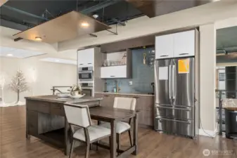 The stylish community kitchen features contemporary cabinetry, a large island, and stainless steel appliances—ideal for entertaining, potlucks, or shared meals. Ample counter space and comfortable seating make it a functional and welcoming amenity.