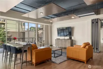 A cozy lounge area with large windows provides plenty of natural light and views of the surrounding community. Comfortable seating and a mounted TV make this the perfect space to relax, watch a game, or connect with neighbors.