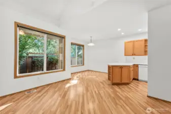 View looking from fireplace corner of living room out to dining room and edge of kitchen. Large window brings in tons of light to the living room. Laminate hardwood flooring throughout main floor.