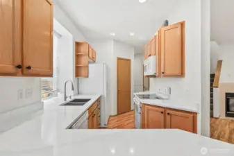 Beautiful new countertops make the kitchen feel extra bright. Stainless sink with double compartments, with window looking out to side yard. Dishwasher located next to sink and across kitchen from glass-top stove/range and microwave. Laminate hardwood flooring throughout main floor.
