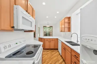 White matching Kitchen appliances including an above-stove microwave, dual-side refridgerator, dishwasher and glass-top stove/range. Laminate hardwood flooring throughout main floor.