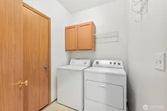 Utility room with Washer & Dryer and small storage area, located on main floor; vinyl floor covering.