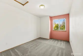 Bedroom 2 with wall-to-wall carpet, window looking out toward frontyard/street. Attic access point in ceiling.