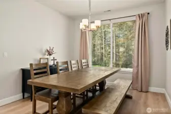 Dining room with LVP flooring and chandelier light fixture. Large window floods the room with light.