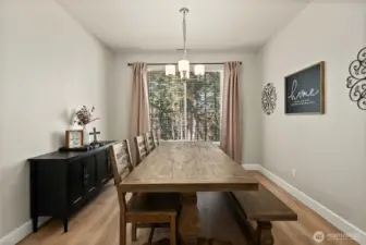 Dining room with LVP flooring and chandelier light fixture. Large window floods the room with light.