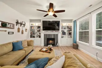 Living room located at the rear of the house, full of natural light, featuring beautiful built-ins along side the fireplace, and LVP flooring.