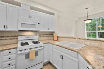 Light and bright updated kitchen cabinets and granite counters with tile backsplash