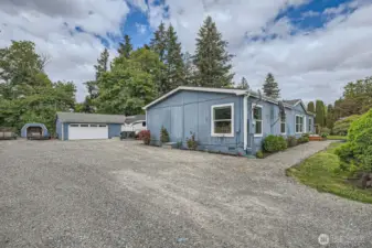 Another view of the ample parking area. The shed to the left is great for storing yard necessities. The two-car garage has a shop area extra storage or work space.