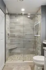 Custom tiled walk in shower, with seating and upscale showerhead.