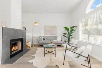 Sun-filled living room with vaulted ceilings, picture windows, and a sleek fireplace creating a modern yet cozy atmosphere.